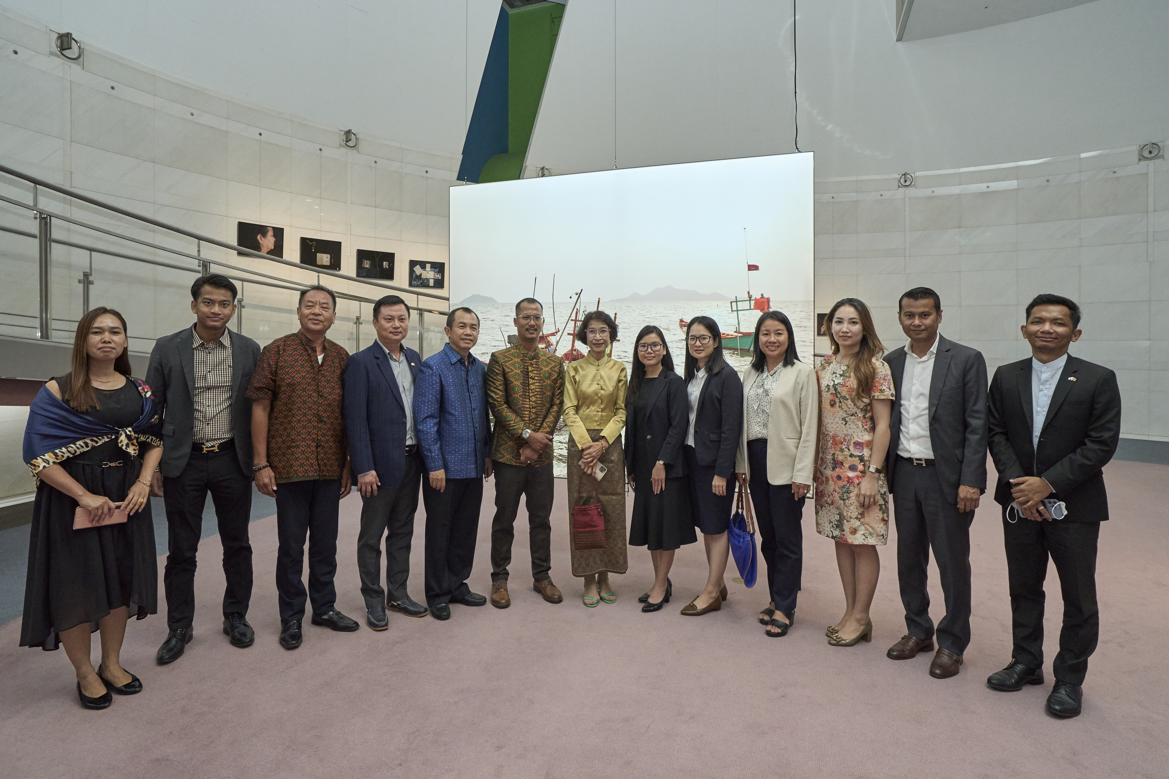 Slider Image A group of exhibition launch attendees stand in front of one of Kim Hak's artworks